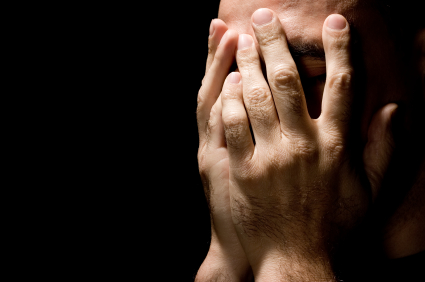 Depressed man with hands clasped over his face