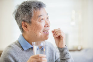 older asian man taking cholesterol medication